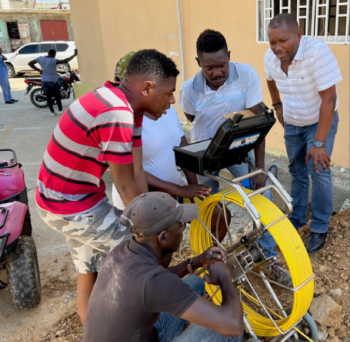 Community members in Haiti operating and inspecting water system equipment