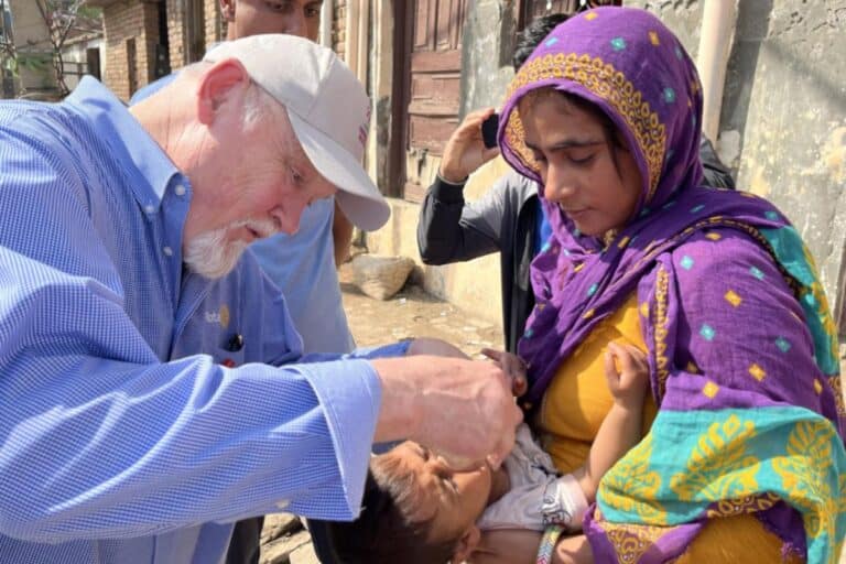 Rotarian administering polio drops to a child in India