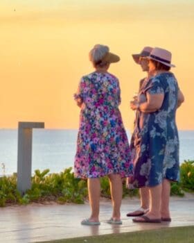 Three women silhouetted on a beach at sunset