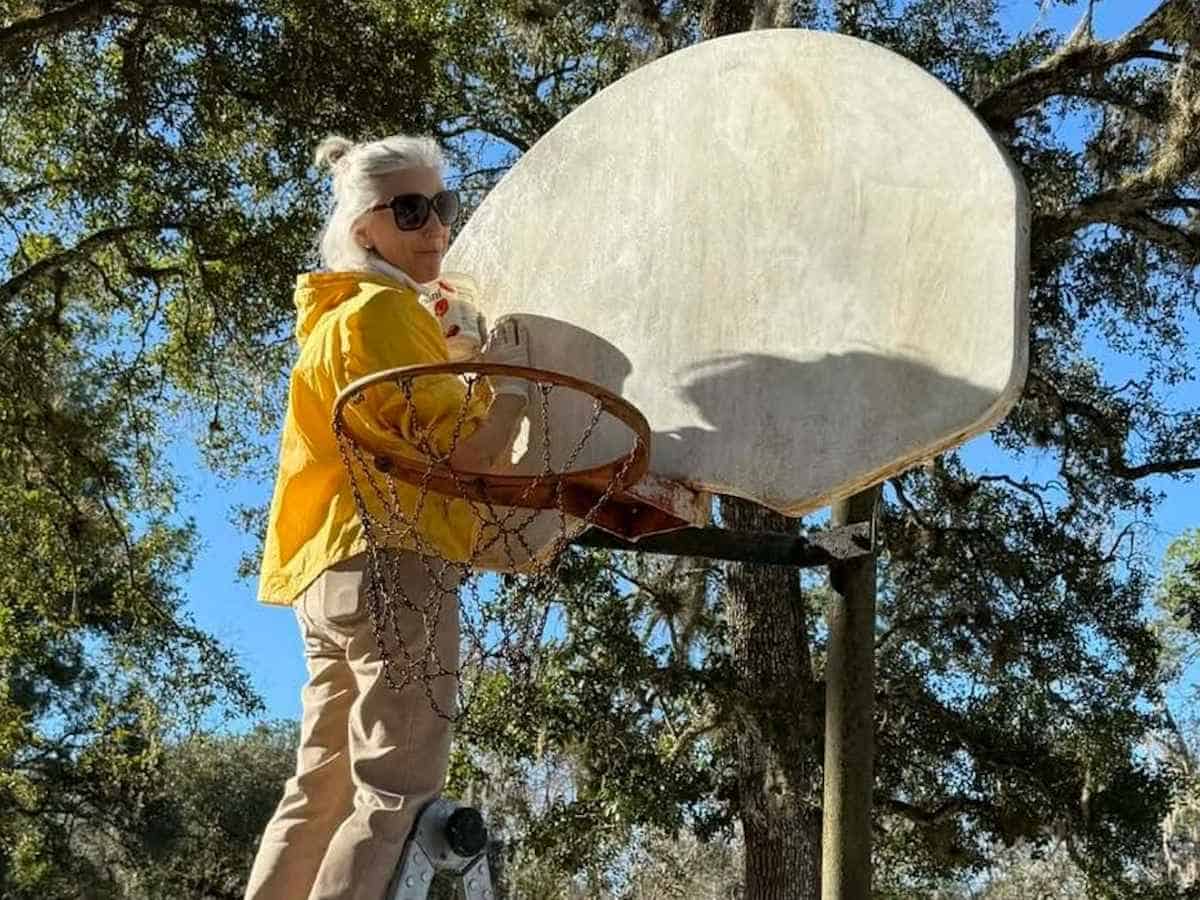Virtual_Youth Global Travelers member cleaning a basketball backstop in a local park.